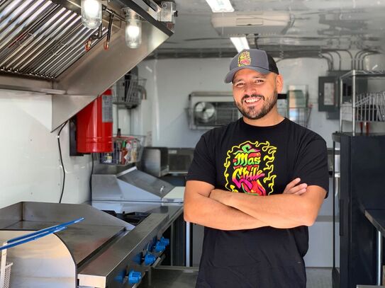 Photo of Mundo Kelley Mendoza, owner of Mas Chile in the back of his food truck